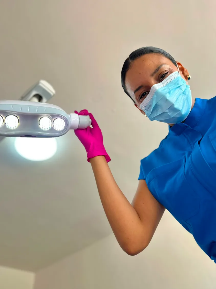 Dra. Cindy Parrazal en consulta ajustando la lámpara dental